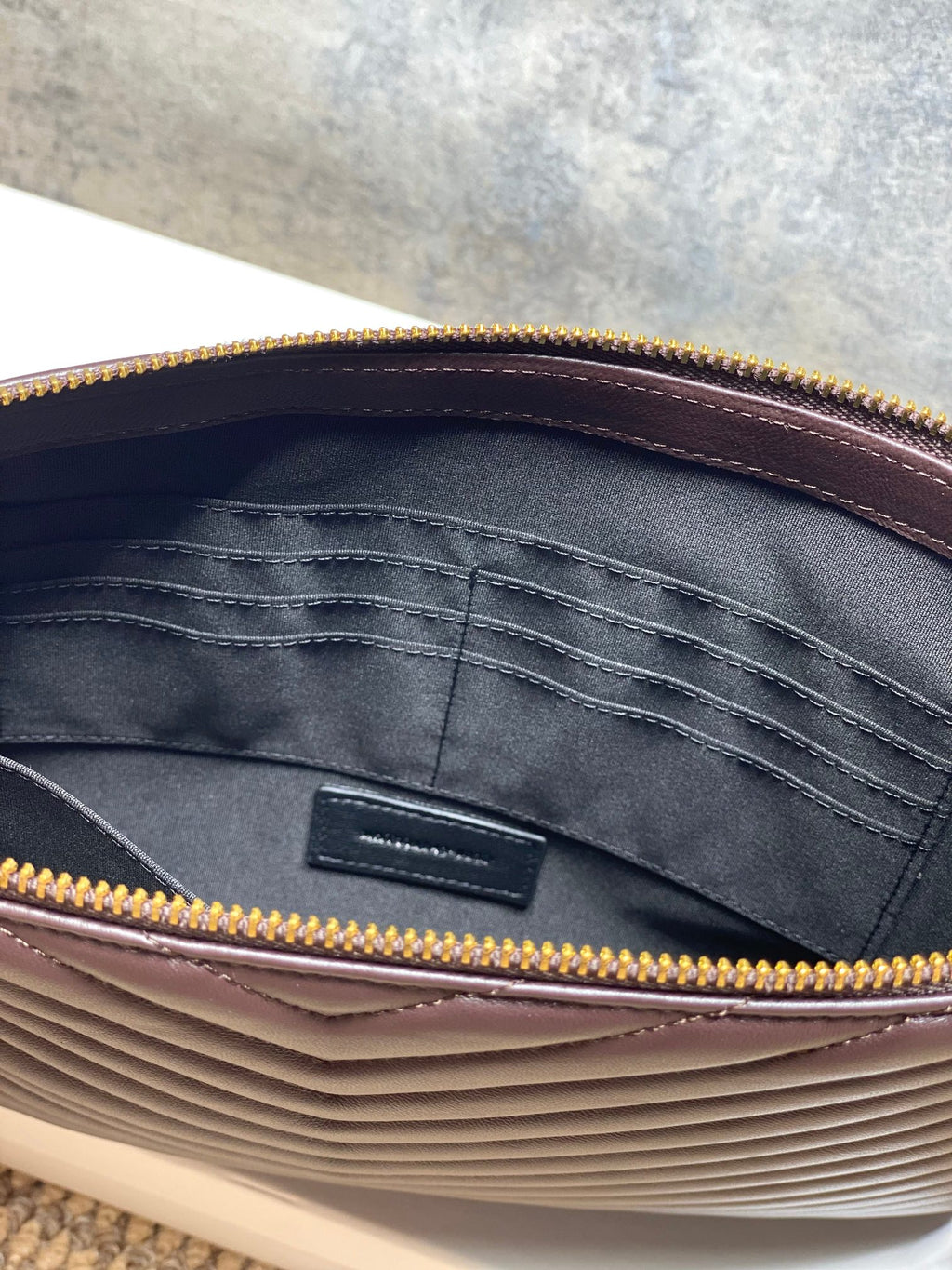 YSL small handbag interior with dark fabric lining and gold zip trim around the opening