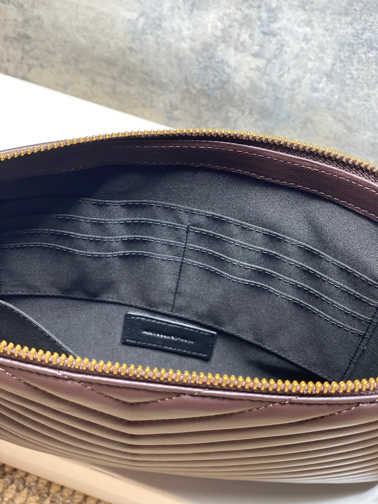 YSL small handbag interior with dark fabric lining and gold zip trim around the opening