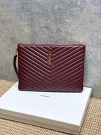 YSL quilted bag in burgundy with chevron stitching and gold YSL logo on front.