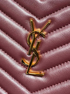 Close-up of YSL logo charm on burgundy quilted leather bag with gold hardware.