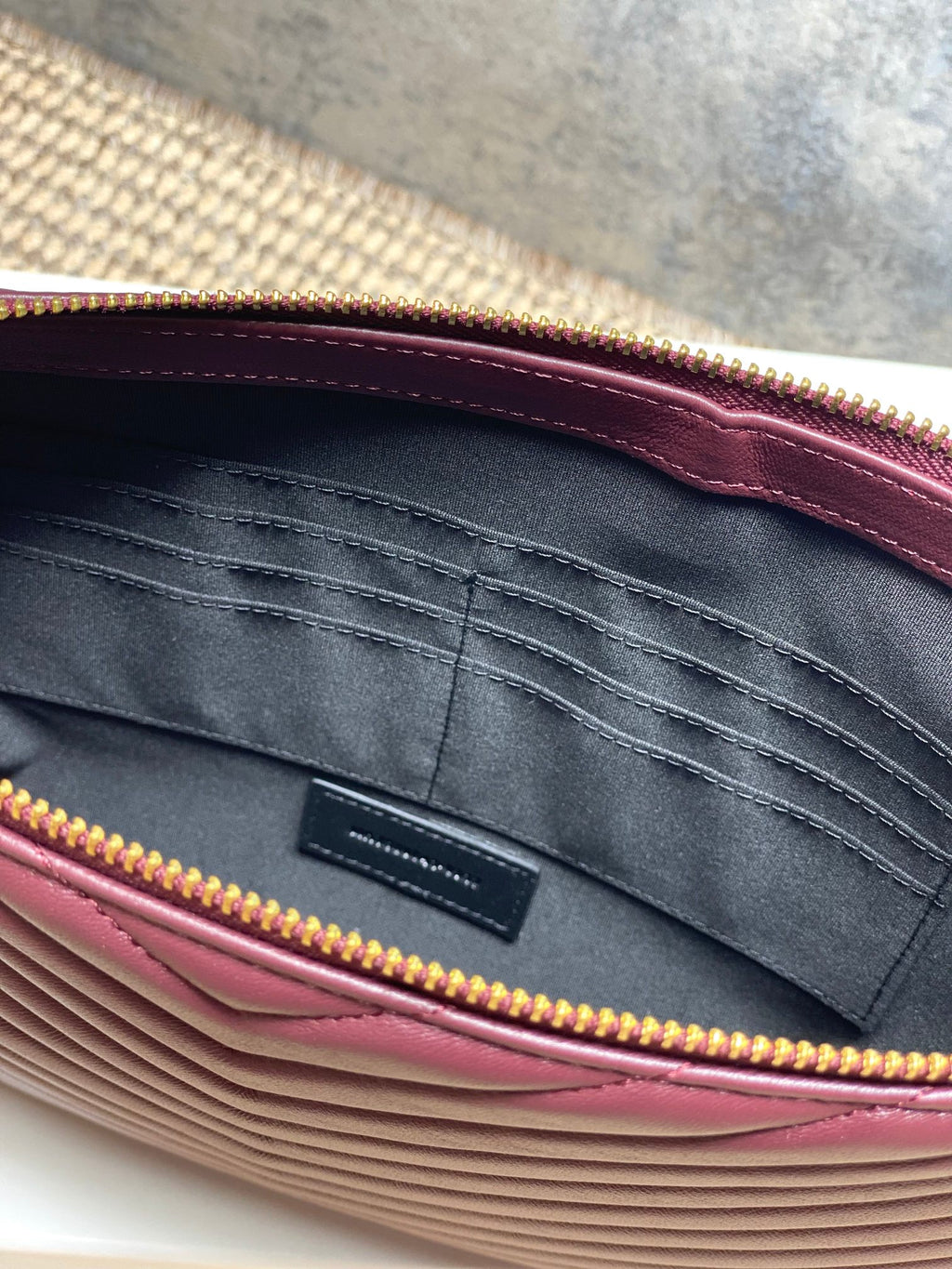 Inside view of burgundy bag with gray lining and gold zipper trim
