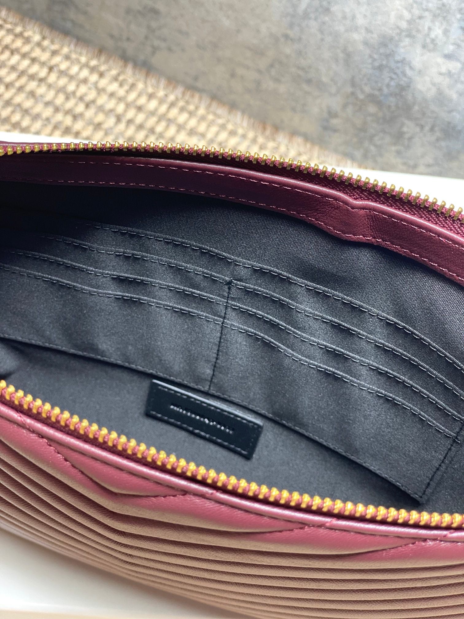 Inside view of burgundy bag with gray lining and gold zipper trim