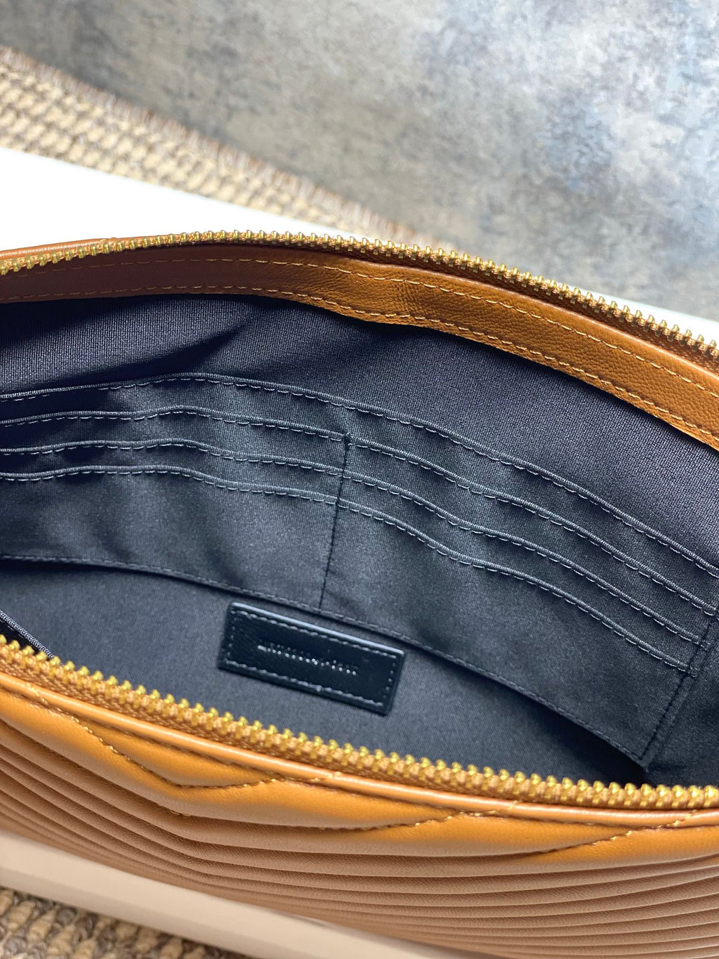 Inside view of YSL small quilted bag: navy lining, pocket, gold zipper edge