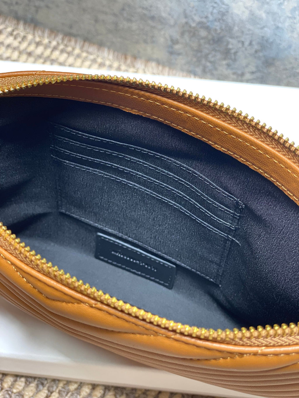 Small bag interior with navy lining, card slots, and gold zipper trim, brown