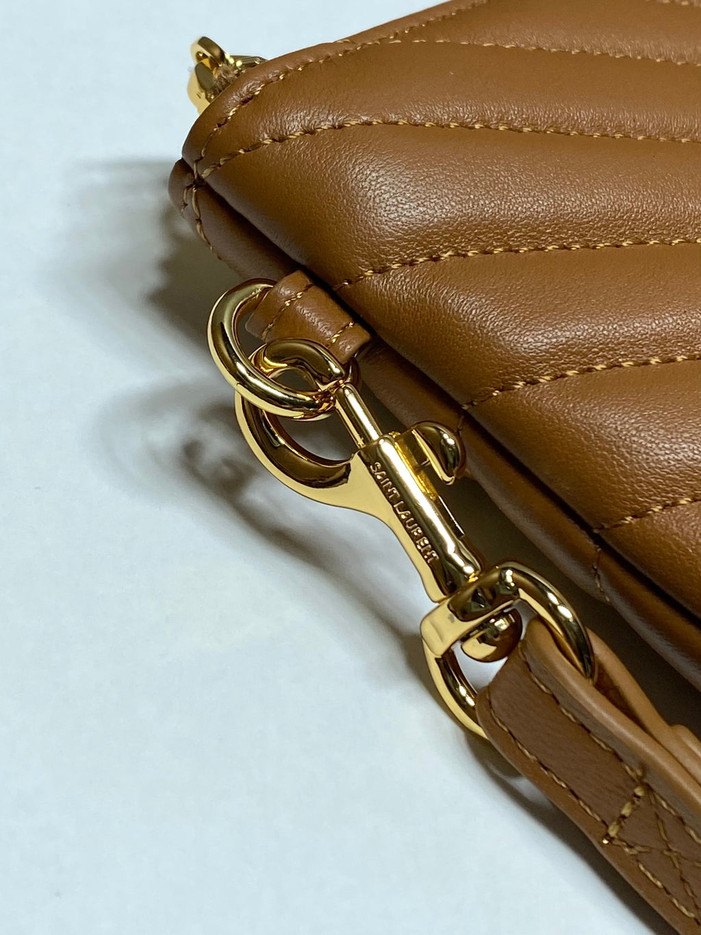 Gold-tone zipper hardware and clasp on chevron quilted leather clutch, tan-brown.
