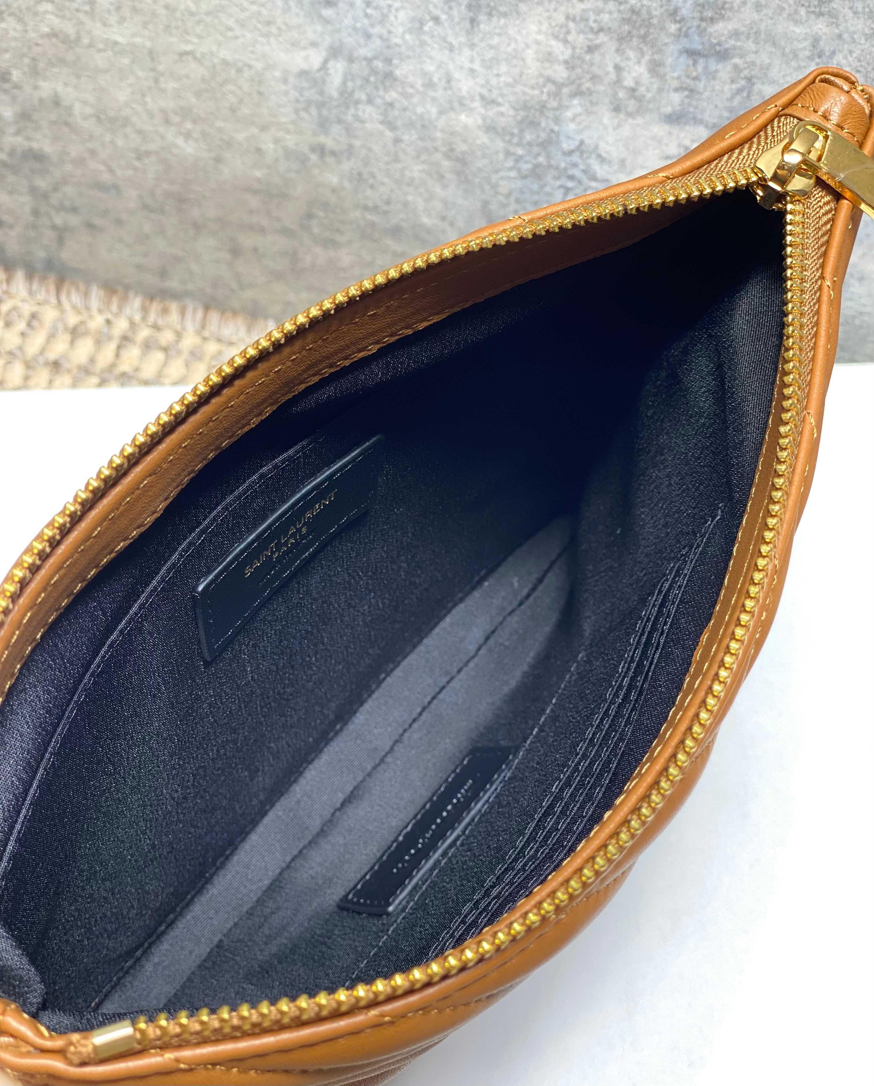 Small bag interior with navy lining and card slot, gold zipper edge, brown leather