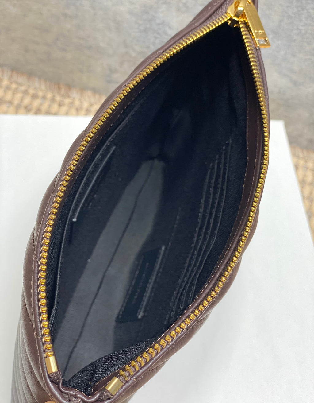 Small YSL bag side opening showing dark lined interior and gold zipper edge.