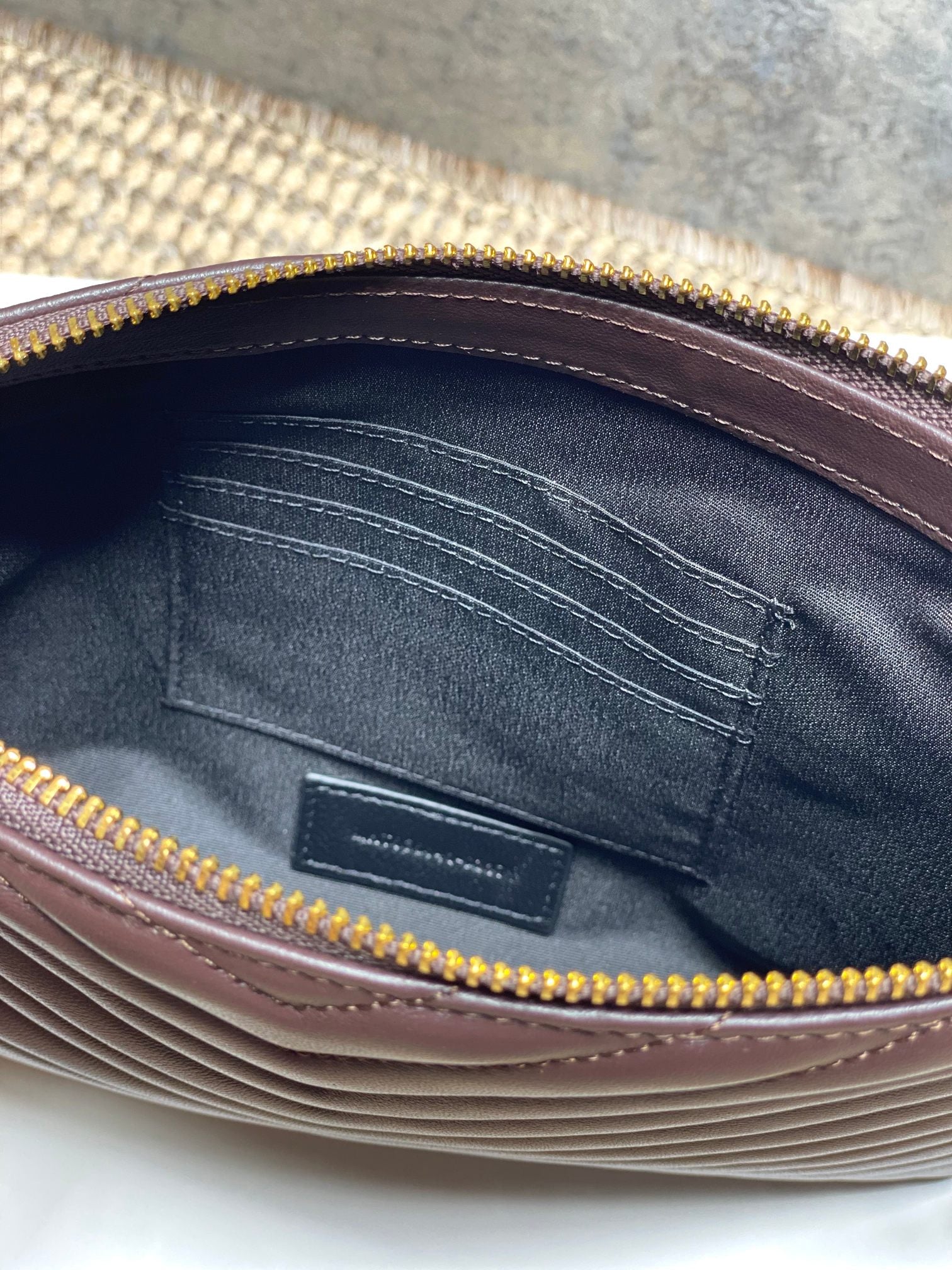 Small YSL bag interior view with stitched lining and gold-tone zipper opening.