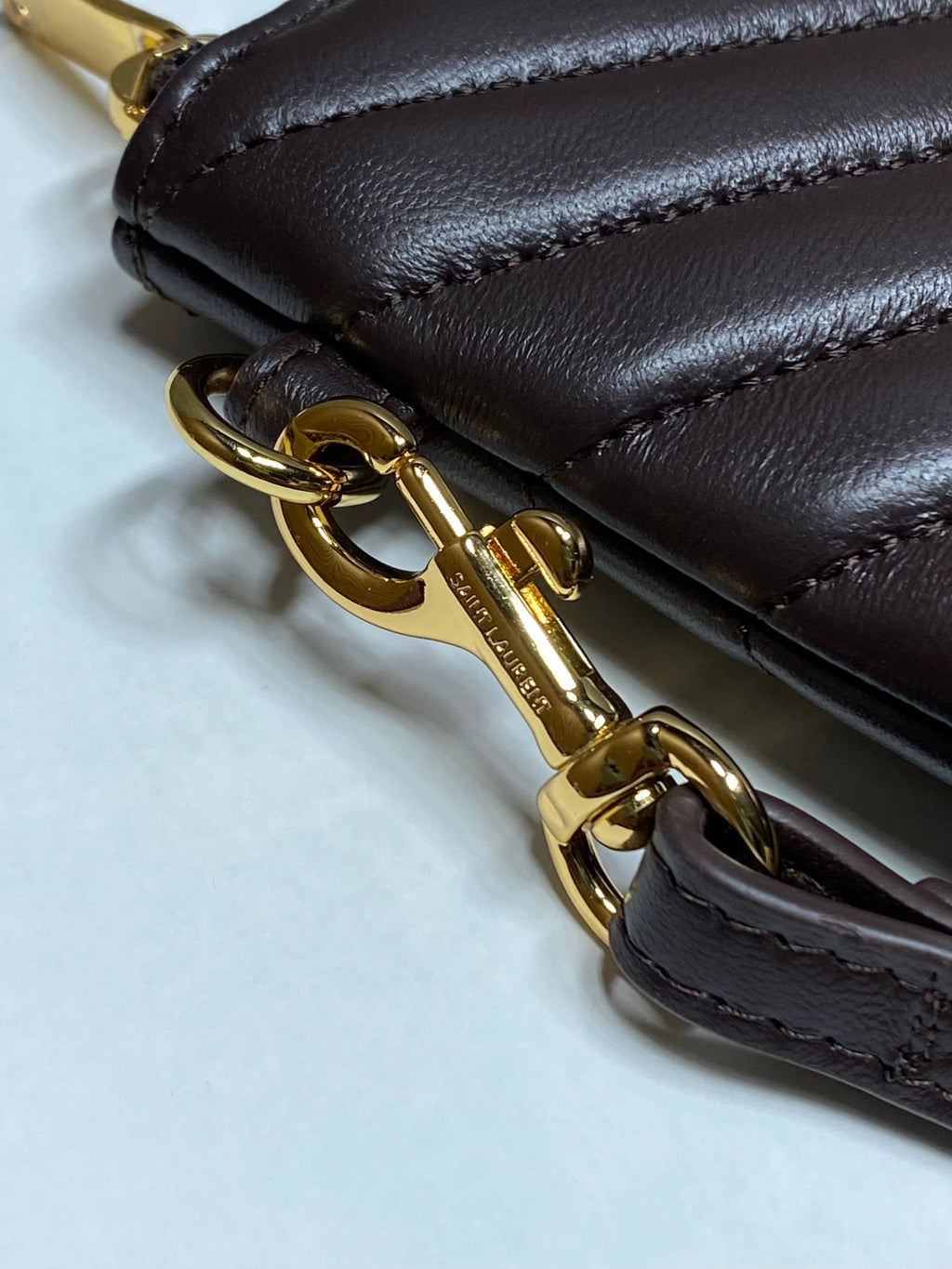 Close-up of gold chain and clasp on dark brown leather bag