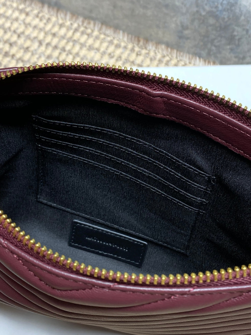 Interior of burgundy quilted bag with dark lining and zipper opening