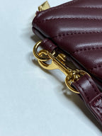 Gold-tone clasp and hardware on burgundy leather strap near zipper