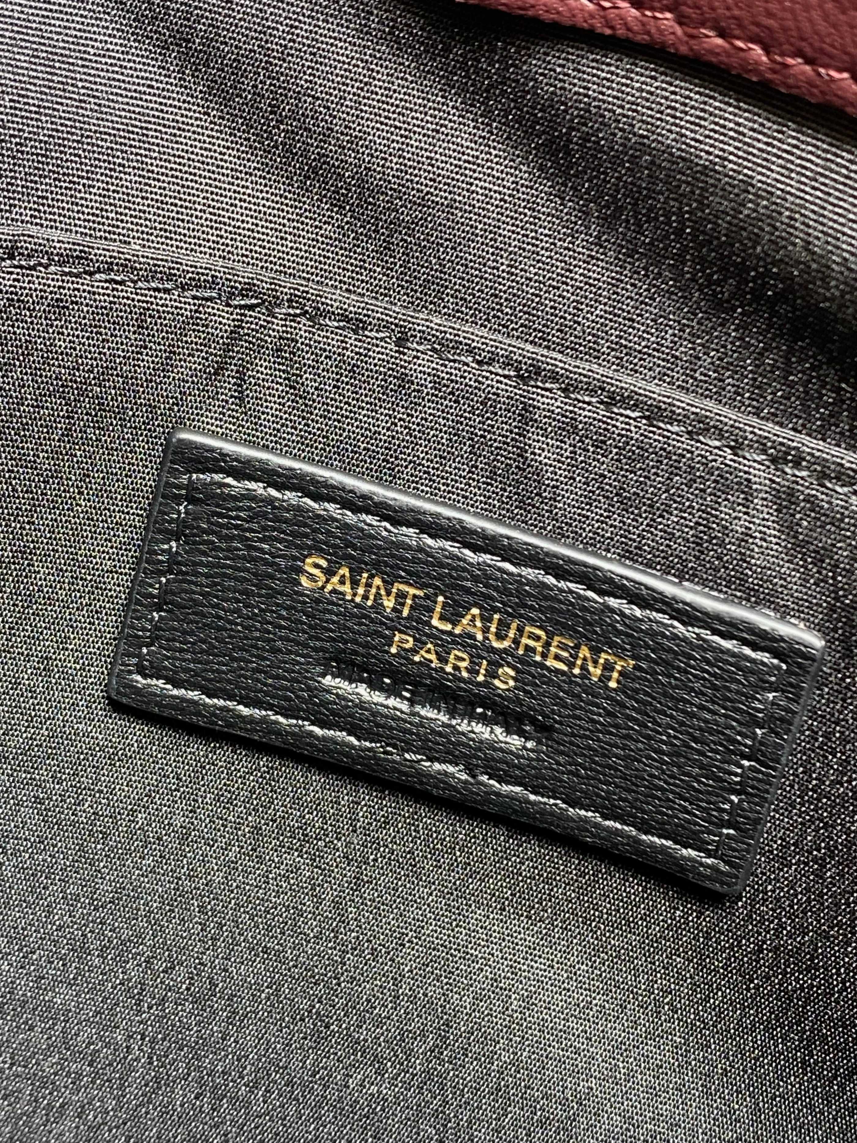 Fabric interior label reading “SAINT LAURENT PARIS” on gray lining