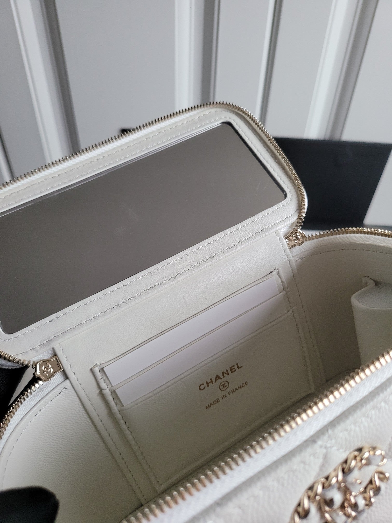 Chanel white quilted bag open view showing interior compartments and zip closure