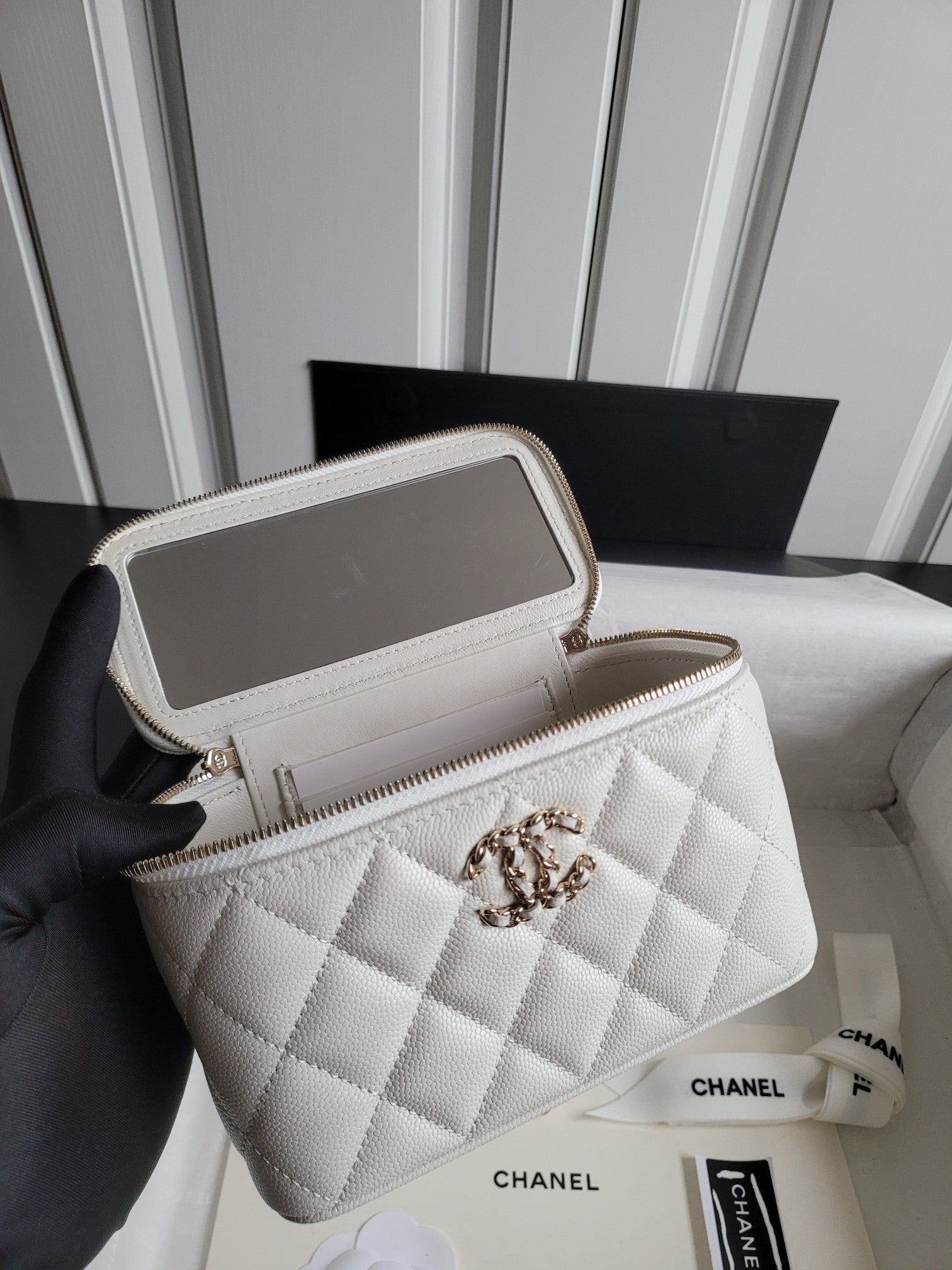 Chanel white quilted crossbody bag held open, showing interior and chain strap