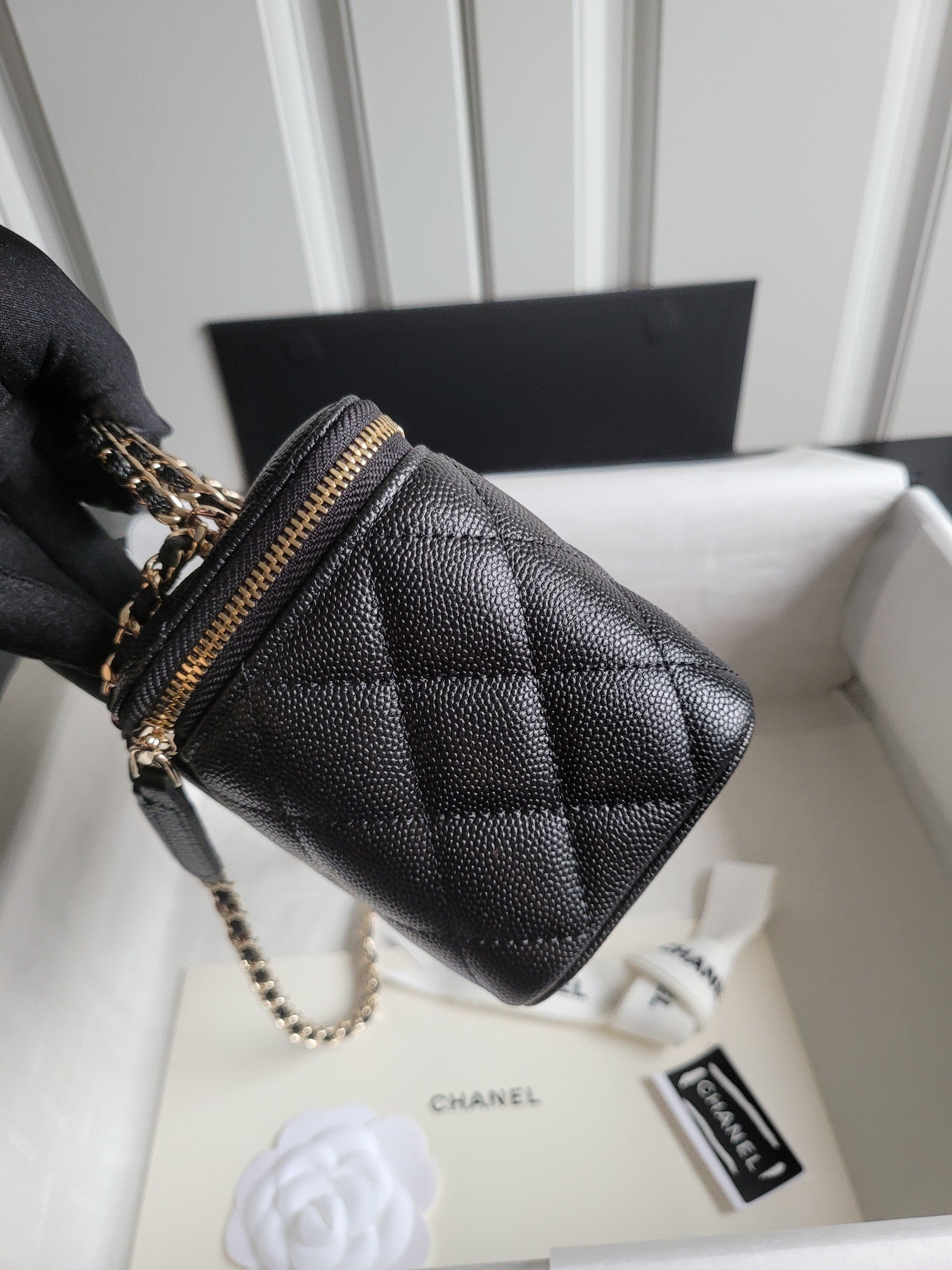 Chanel quilted mini handbag in dark color with side view, chain strap, and gold zip