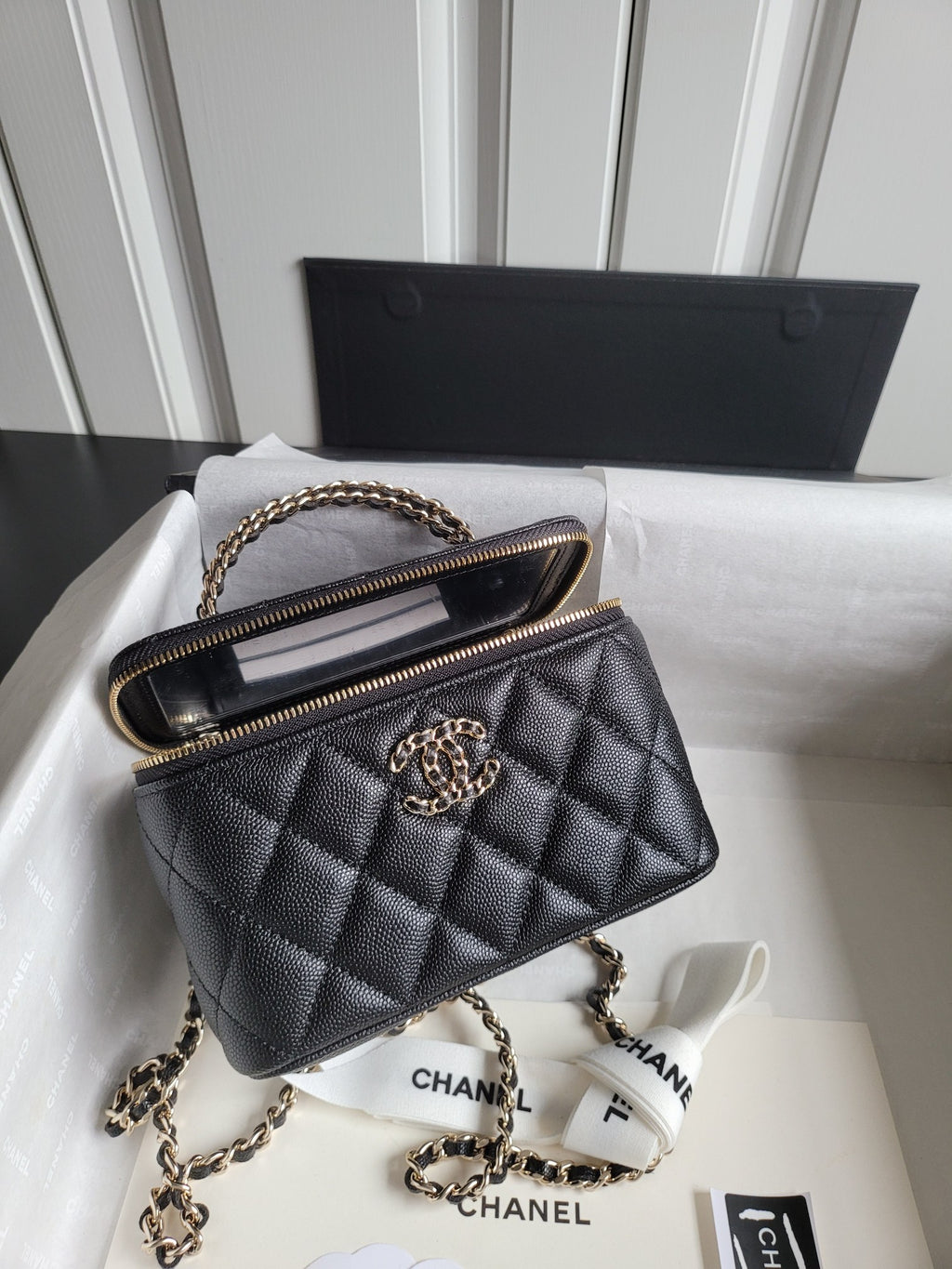Chanel quilted shoulder bag with gold chain strap and front CC logo, top zip closeup