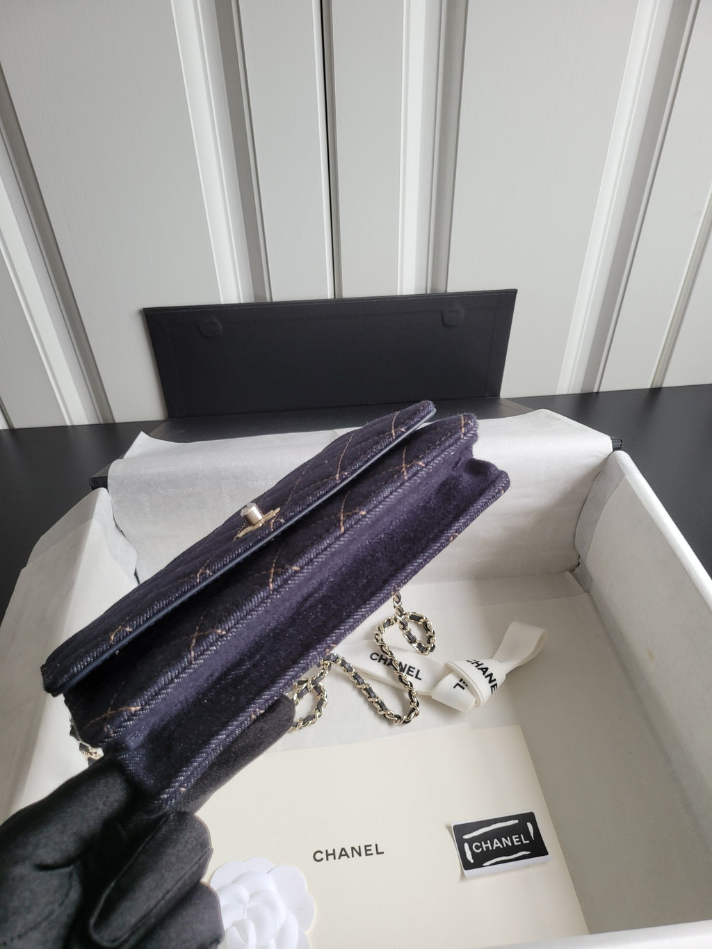 Long quilted navy Chanel shoulder bag with chain strap, held in hand