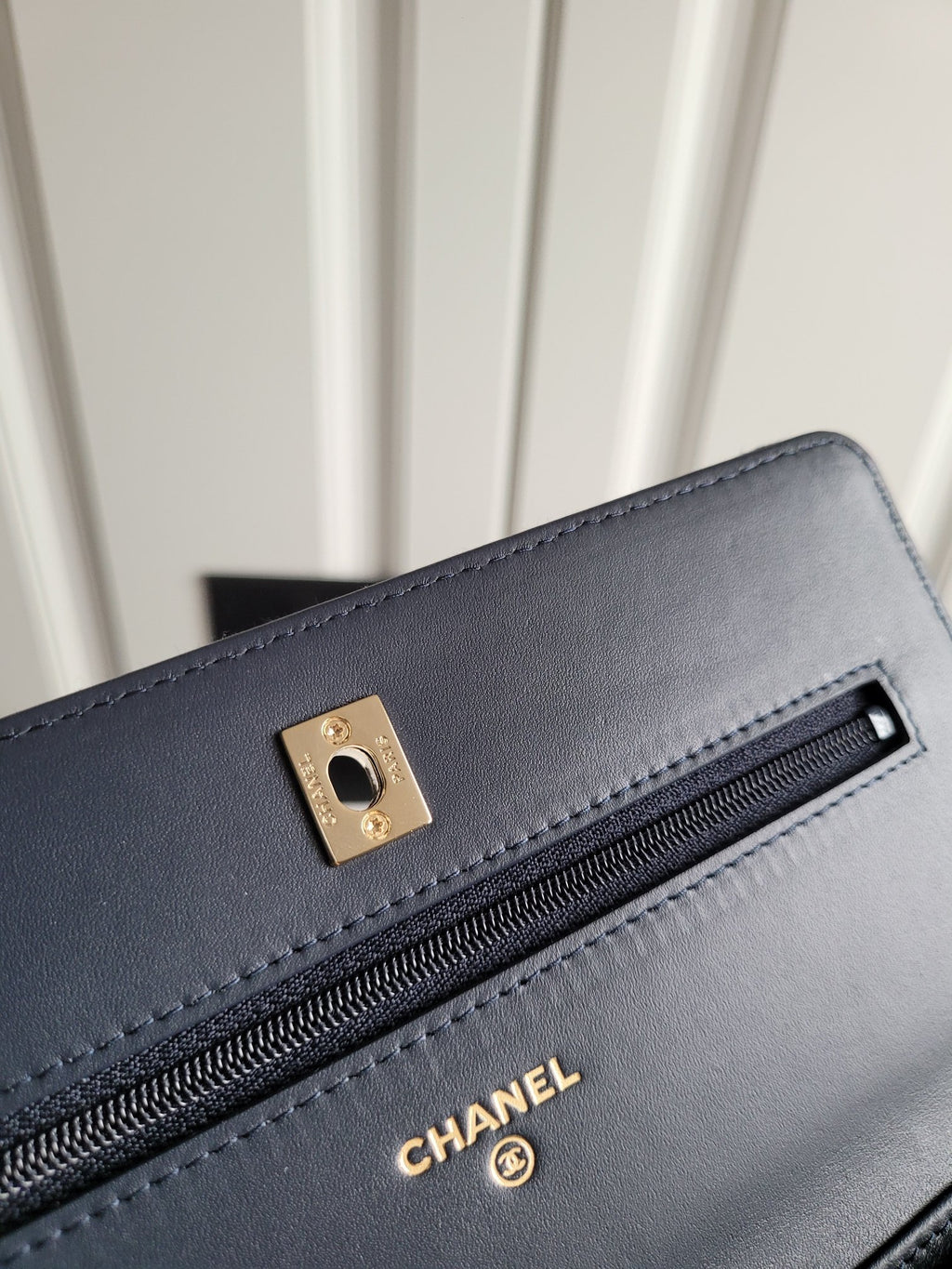 Navy Chanel leather shoulder bag front detail with gold buckle and zipper pocket