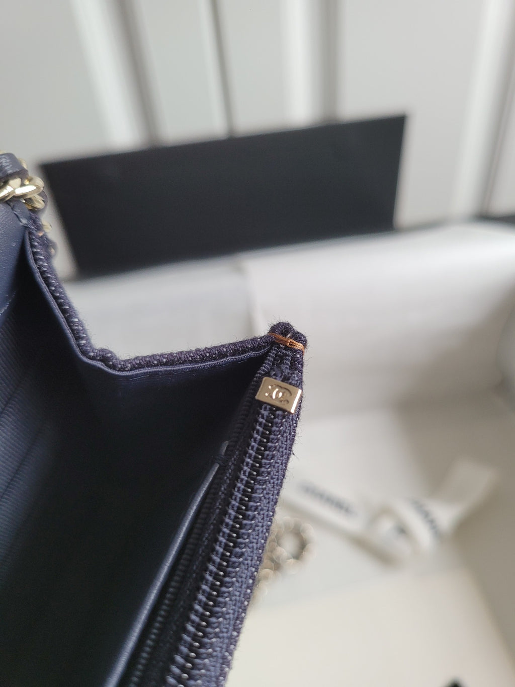 Navy Chanel bag corner with zippered pocket and gold-tone clasp at edge