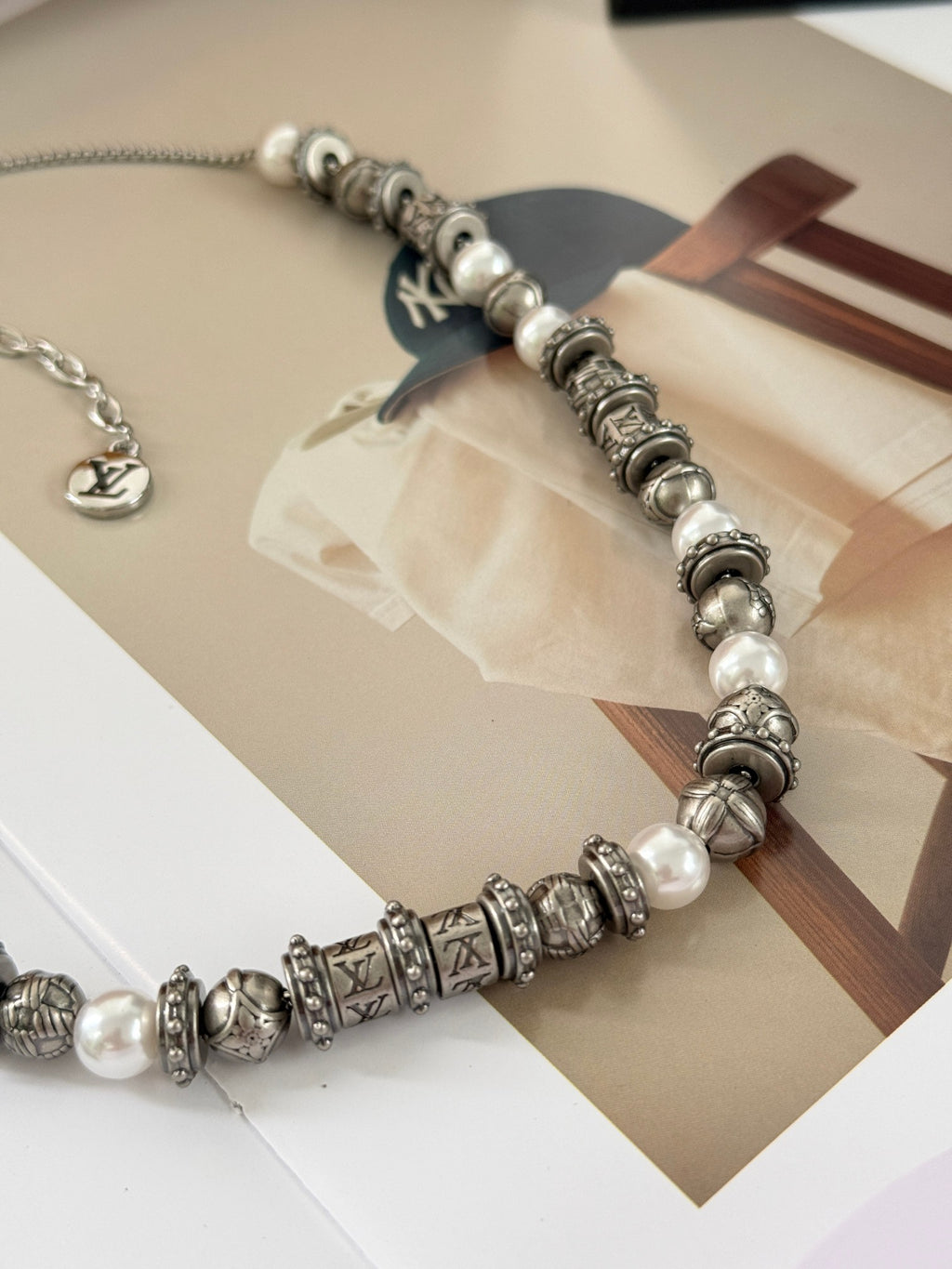 Louis Vuitton beaded necklace with silver-tone stations, pearl-like beads, and charm