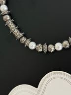 Louis Vuitton necklace detail with pearl-like beads and engraved silver-tone links