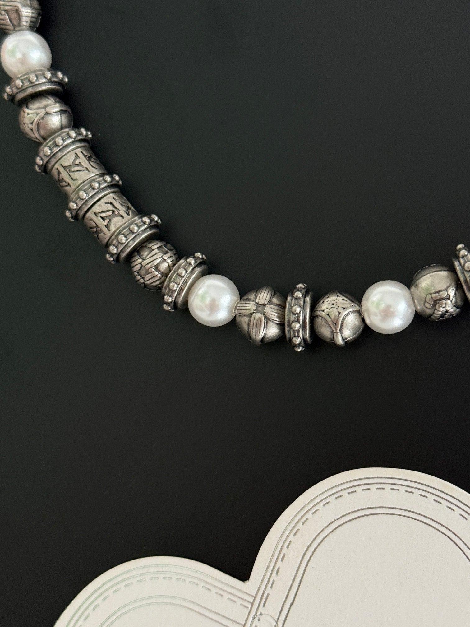Louis Vuitton necklace detail with pearl-like beads and engraved silver-tone links