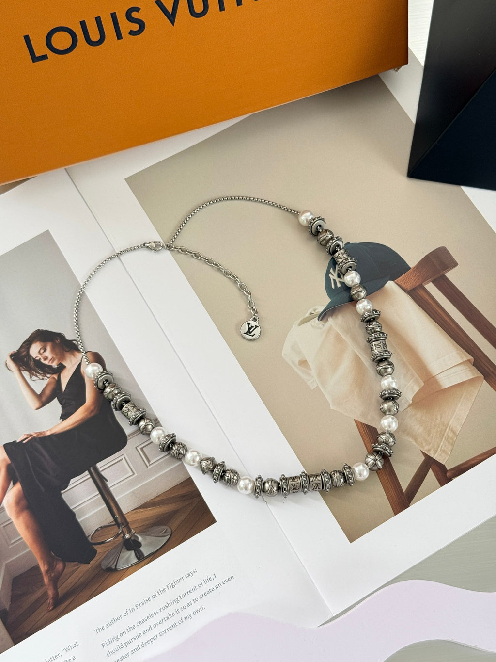 Louis Vuitton beaded necklace on packaging, showing pearl-like beads and silver logo charm
