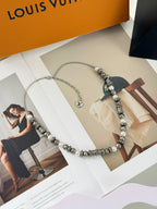 Louis Vuitton beaded necklace on packaging, showing pearl-like beads and silver logo charm