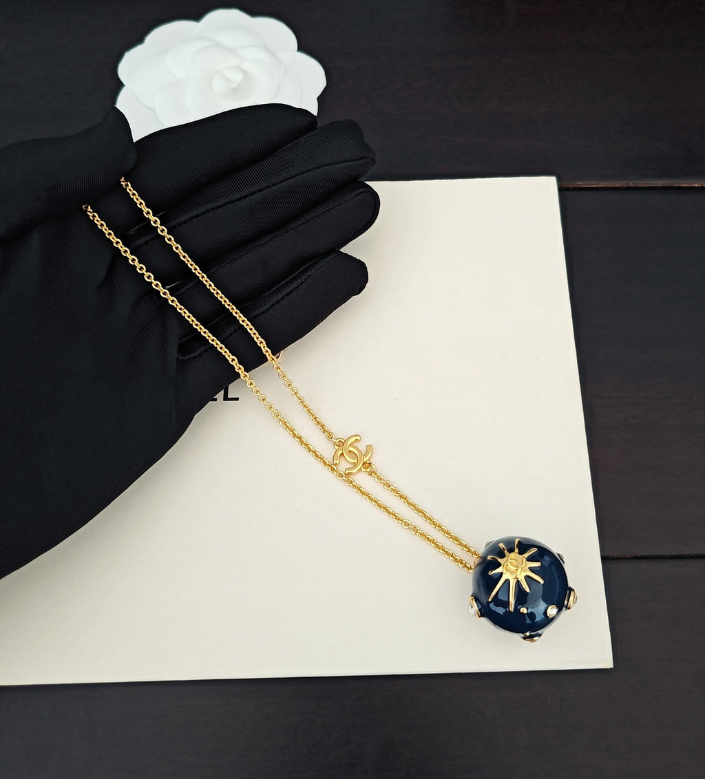 Gold-tone chain necklace with blue round crystal pendant and Chanel charm