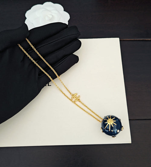 Gold-tone chain necklace with blue round crystal pendant and Chanel charm