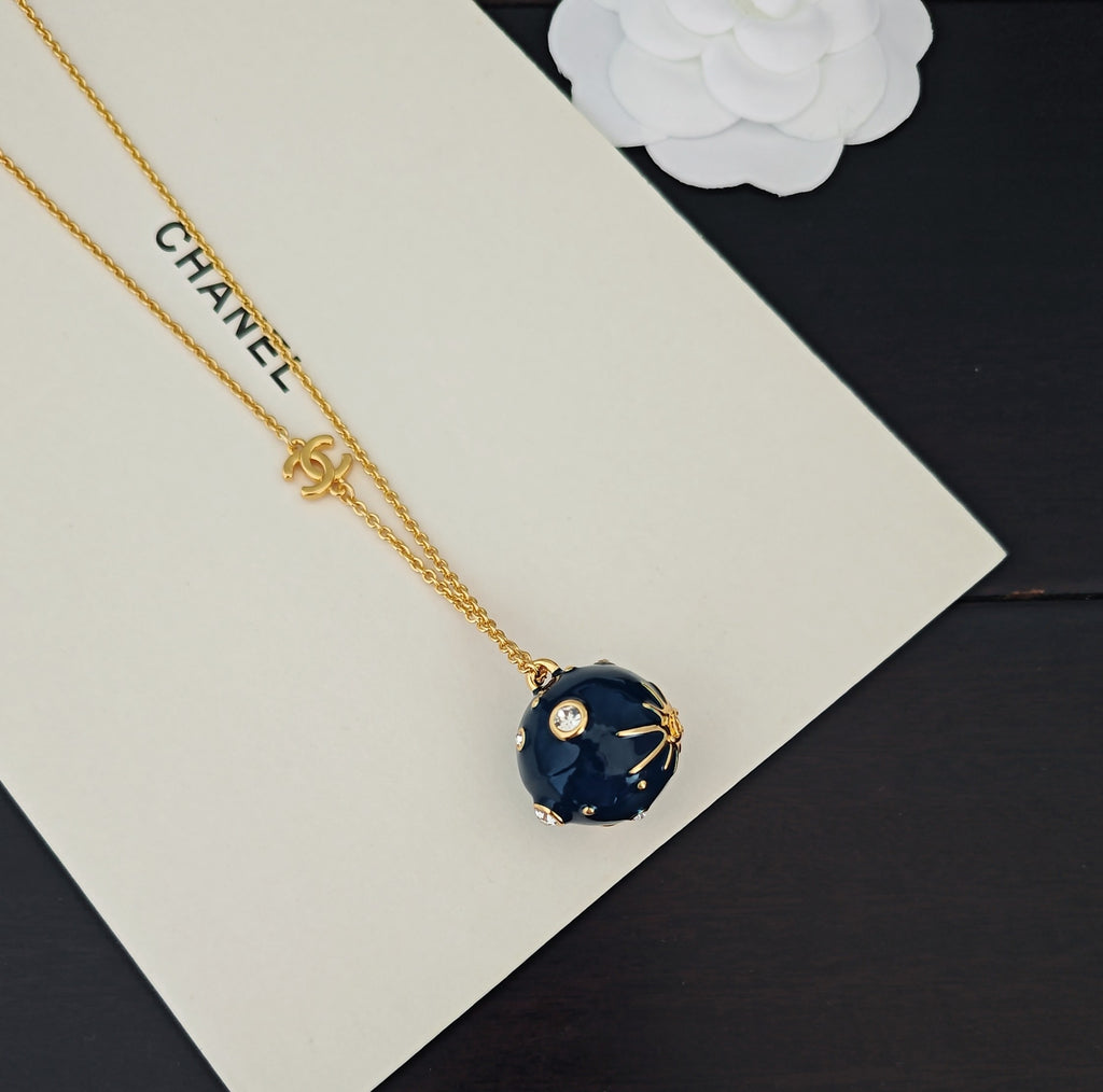 Gold-tone necklace with Chanel text and blue round crystal pendant