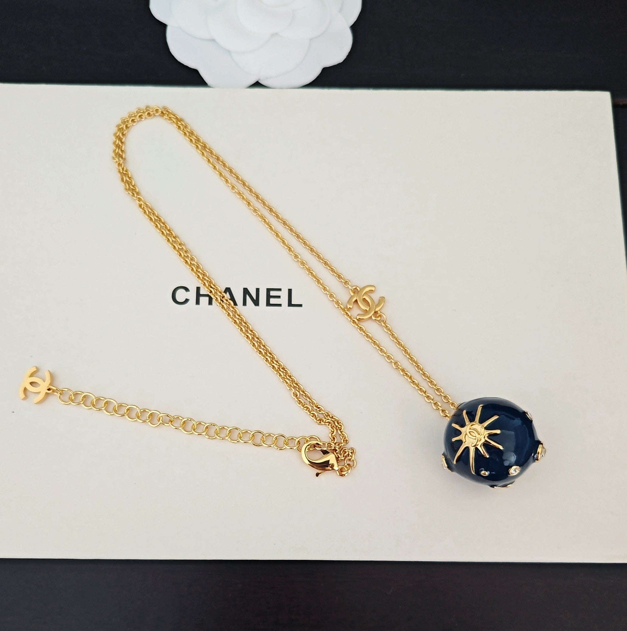 Gold-tone necklace with Chanel logo, blue round crystal pendant, and bow clasp