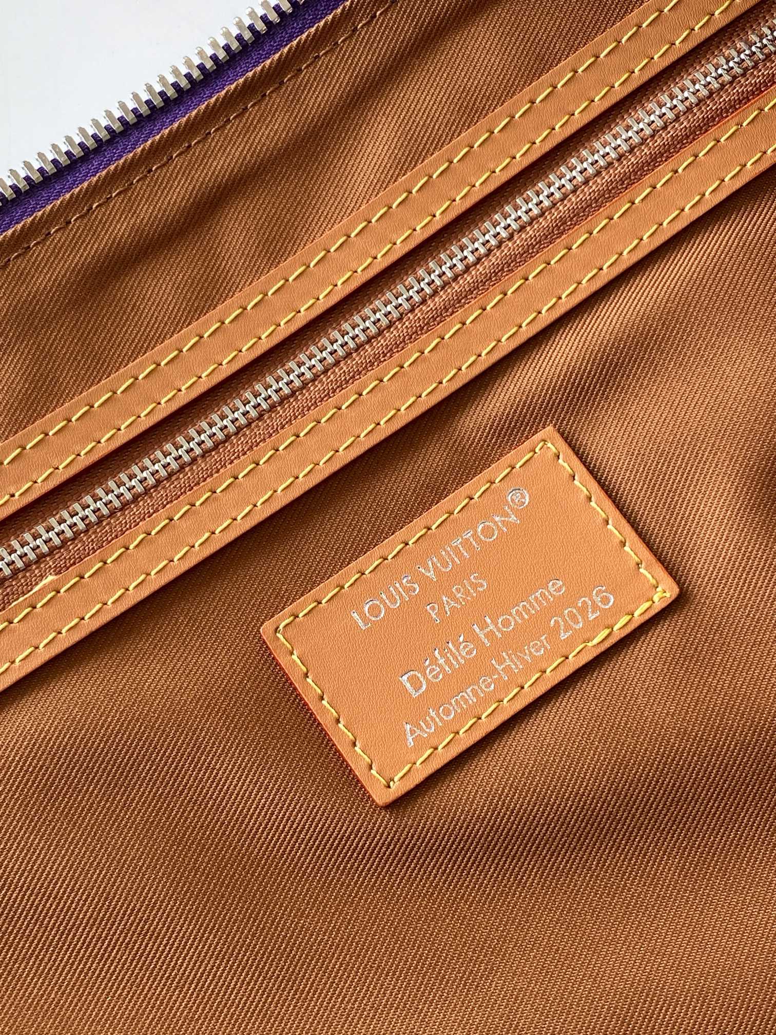 Brown lined duffle bag with leather Louis Vuitton Paris luggage tag and stitching