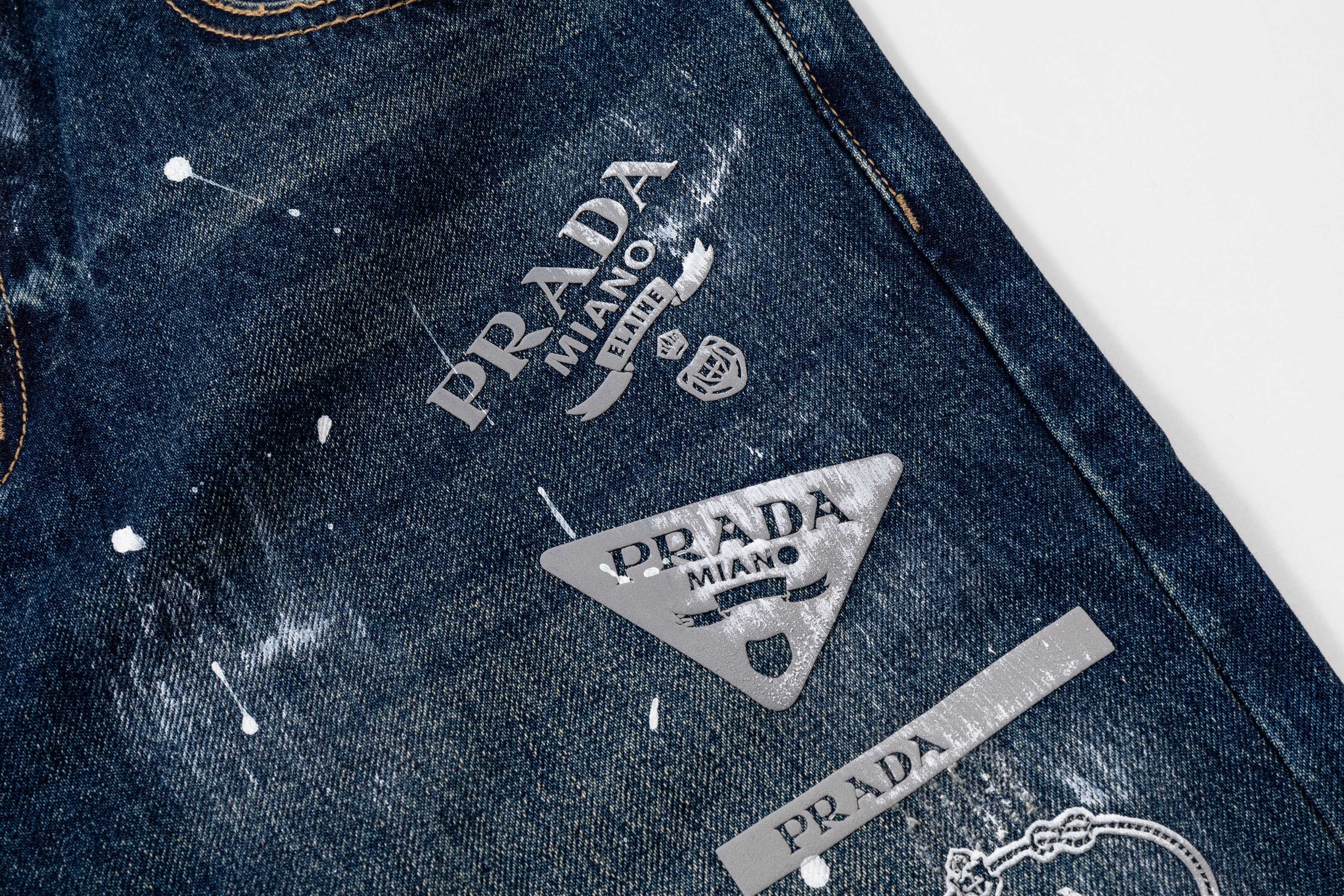 Prada denim pants with Prada and Milano logo patches, dark blue splatter