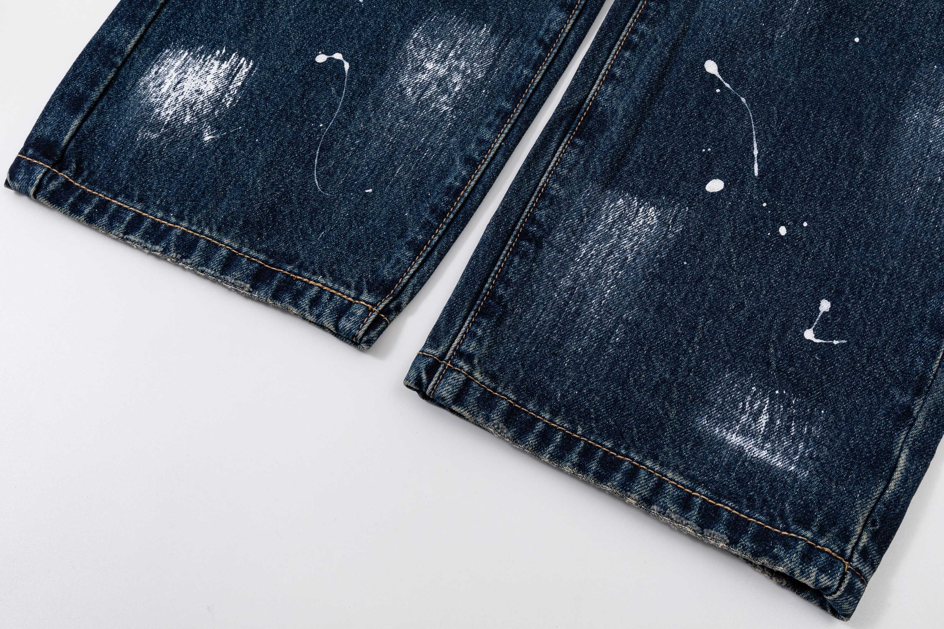 Dark blue denim pants with cuffs and stitched hem, visible distressing marks, flat lay