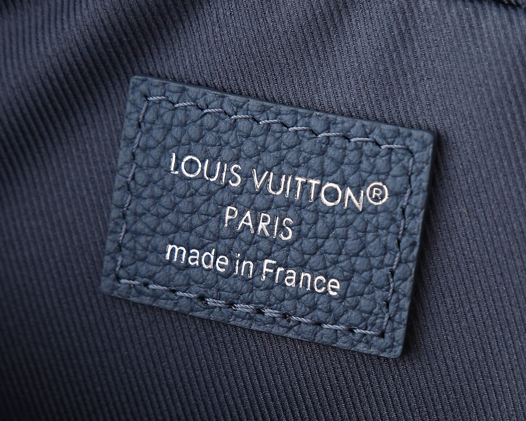 “LOUIS VUITTON” Paris label on blue crossbody bag fabric.