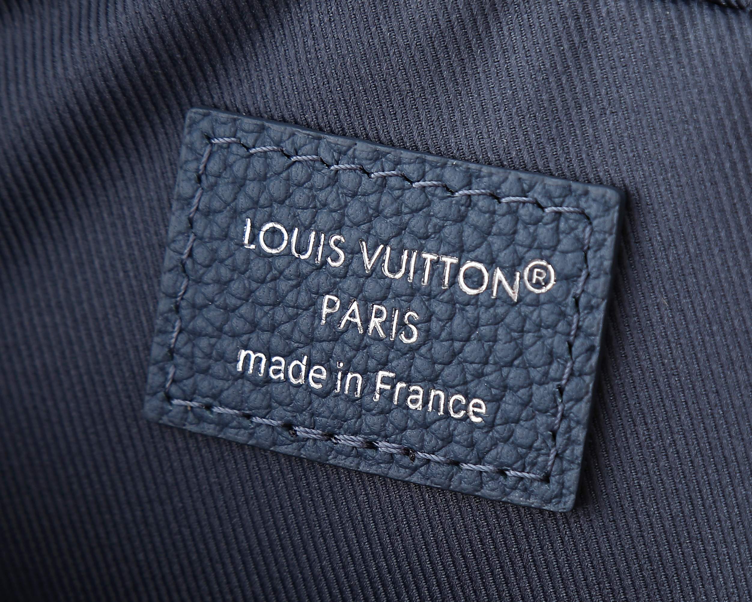 “LOUIS VUITTON” Paris label on blue crossbody bag fabric.