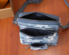 Checkered crossbody bag with multiple zip compartments and small wrist pouch attached.