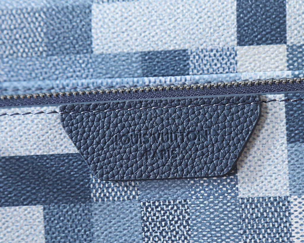 Crossbody bag interior label at zipper seam on blue and white checkered fabric.