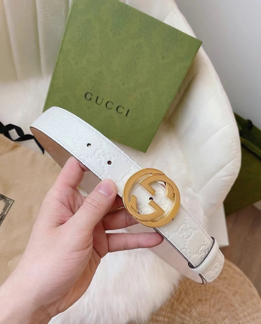 Gucci belt detail view: white embossed strap with gold interlocking G buckle
