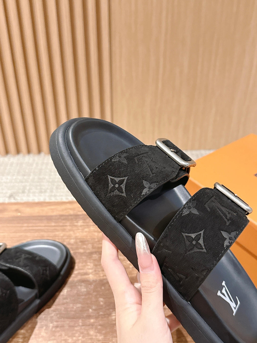 Black monogram slide sandals with two straps, each secured by a silver buckle