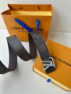 Dark monogram belt with rhinestone buckle on a broad leather strap, adjustable.