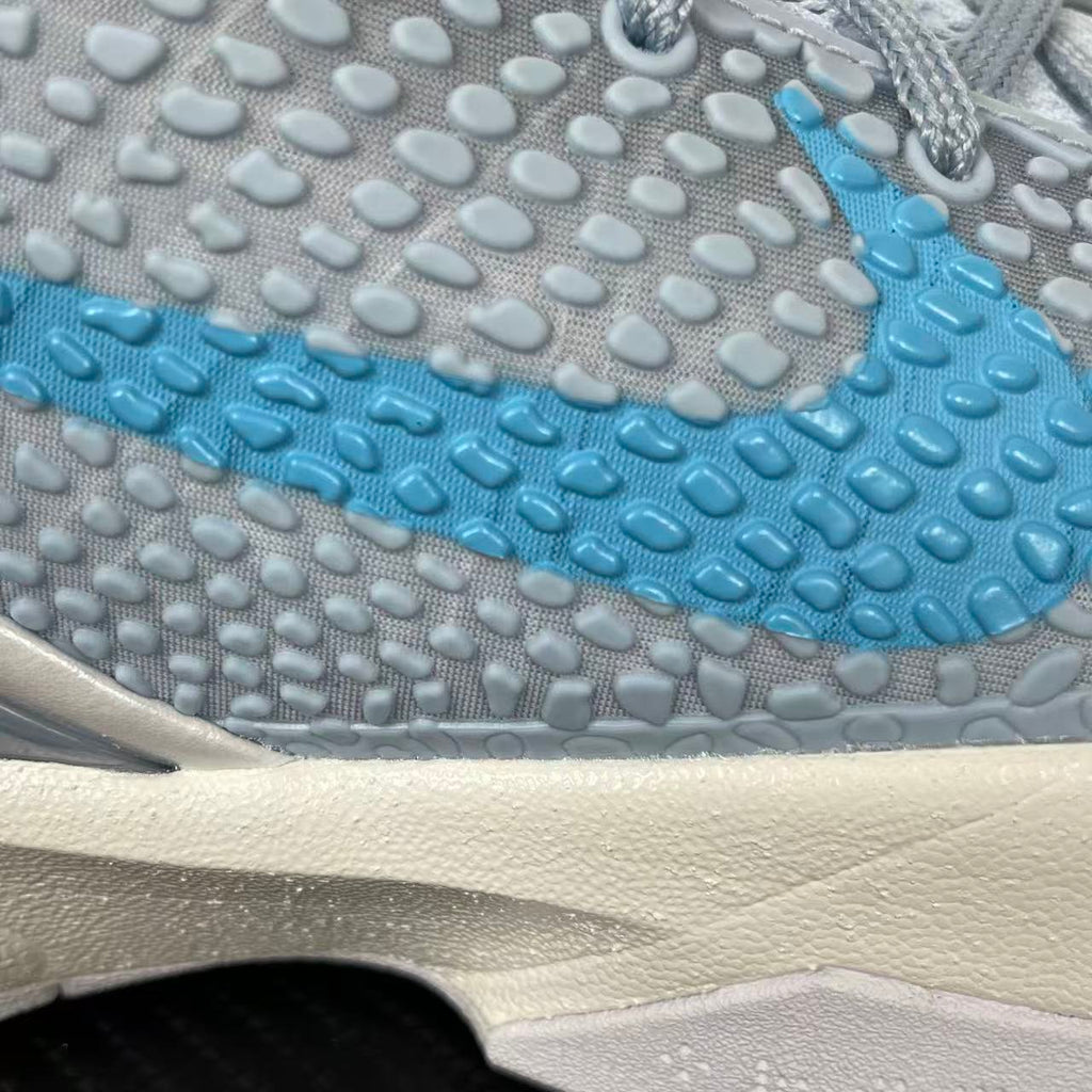 Textured midsole and outsole of light blue and gray basketball shoe with white cushioning.