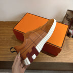 Brown suede sneakers outsole view with thick white tread and red accent panels
