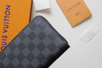 Small Louis Vuitton zip wallet close-up in dark monogram-textured leather.