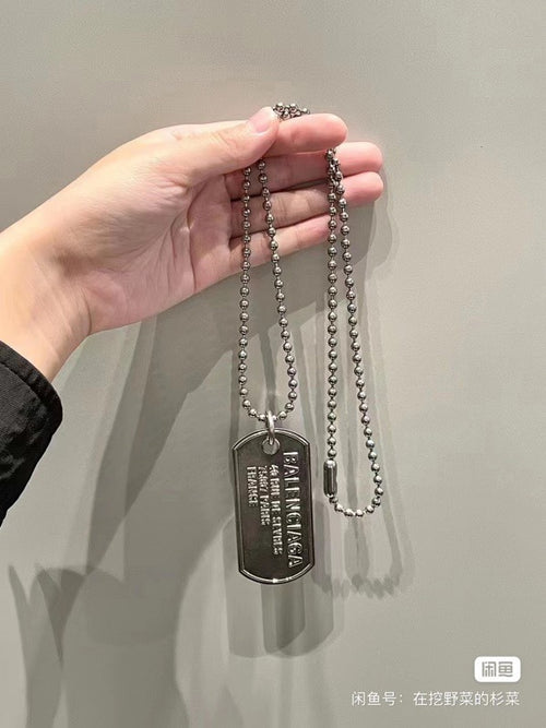 Silver-tone bead necklace with dog tag pendant held in hand