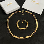 Gold-tone chain necklace and bracelet set with pendant charm, on black fabric