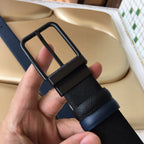 Navy belt close-up with arched buckle and textured strap, hand holding.
