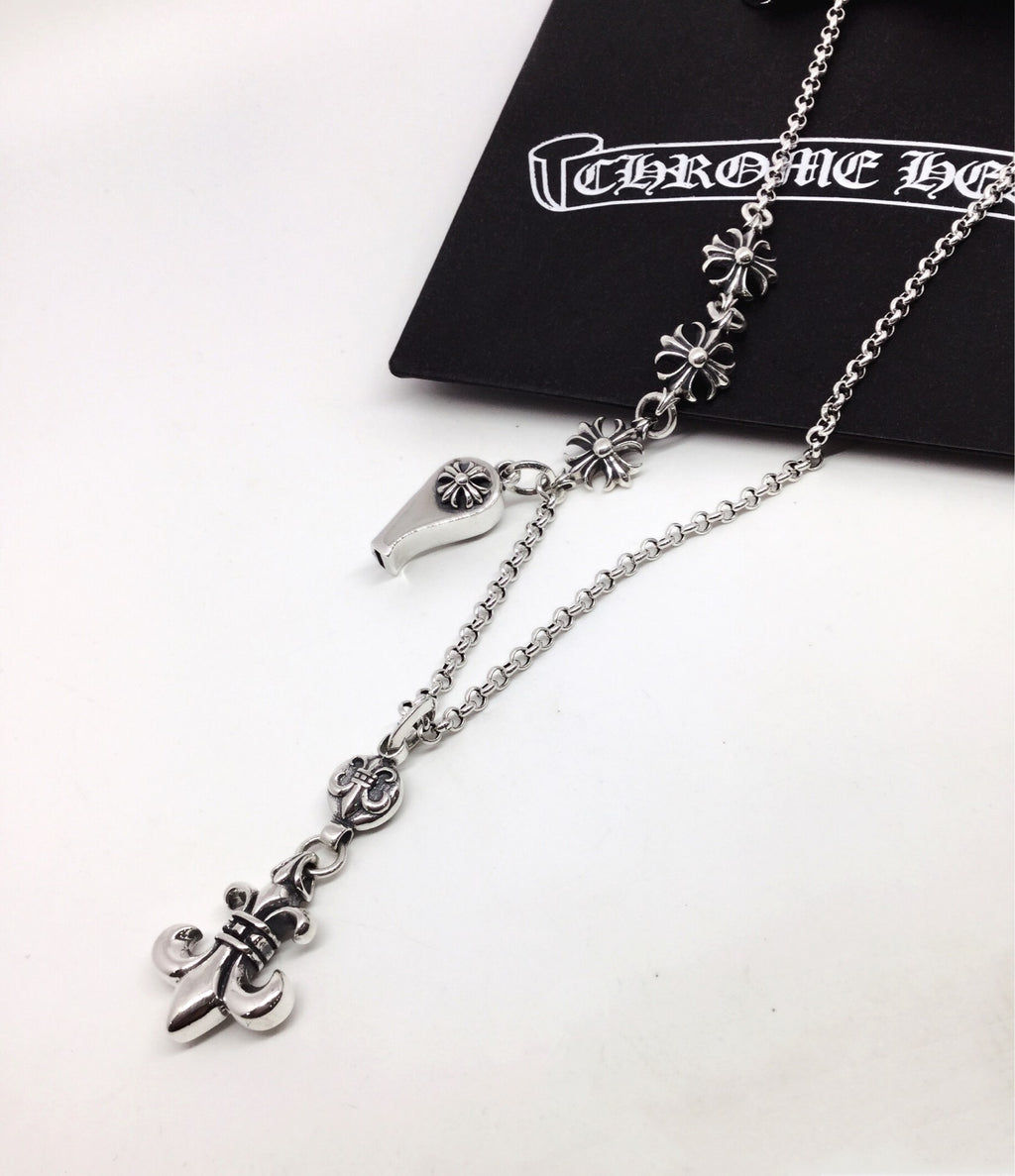 Silver chain necklace with fleur-de-lis links and lock charm, shown near pouch