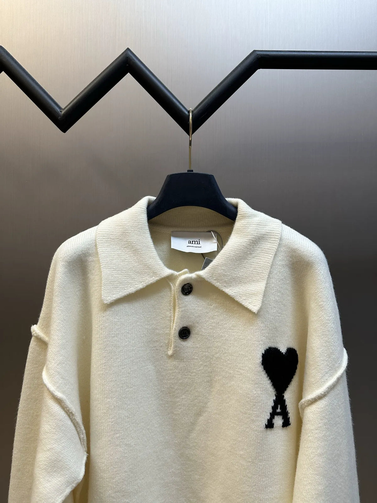 Off-white knit sweater, collared top with black buttons and large heart with A emblem